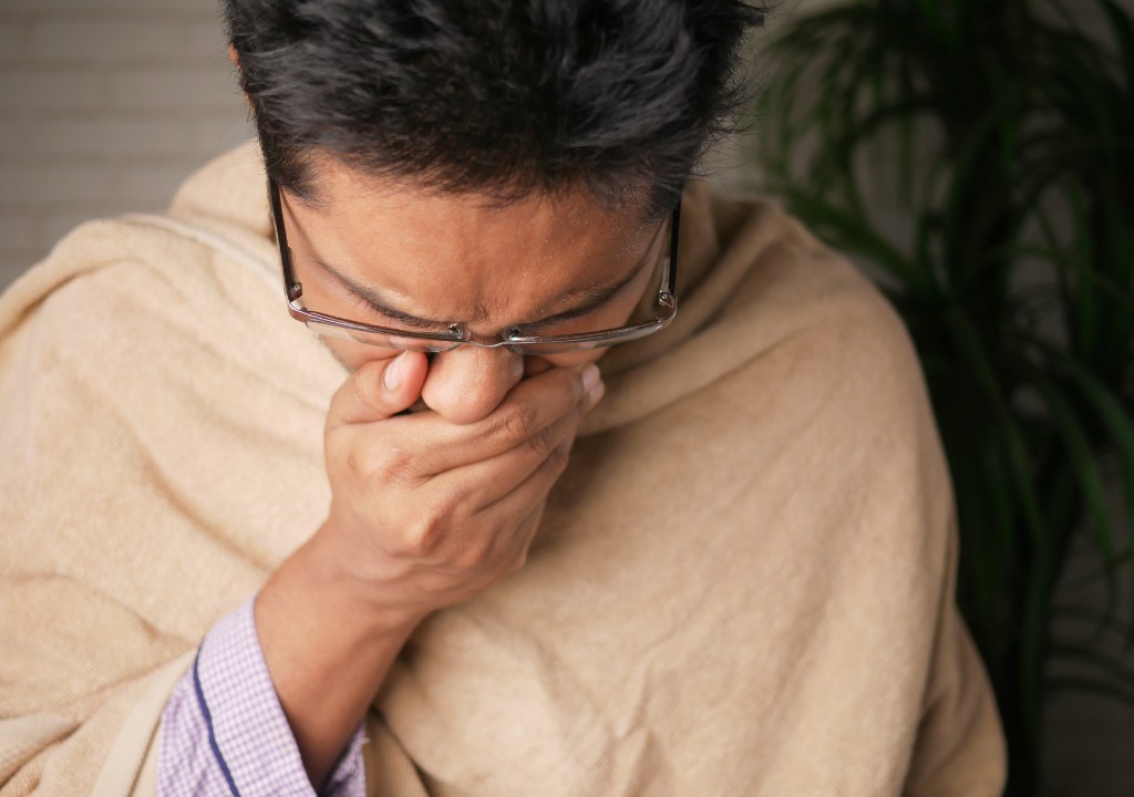 Người trưởng thành bị ho lâu ngày, che miệng khi ho do cổ họng kích ứng và đường thở khó chịu