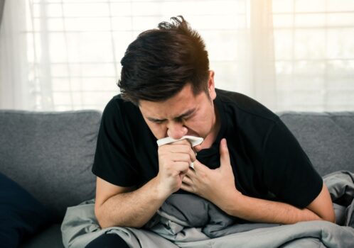 Người đàn ông đang ho và che miệng, minh họa phản xạ ho khi đường hô hấp bị kích thích