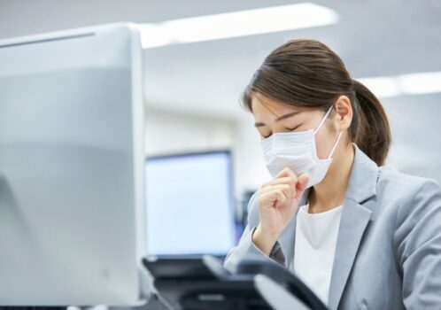 Người phụ nữ ho nhẹ, che miệng khi làm việc thể hiện tình trạng ho thúng thắng do kích thích cổ họng