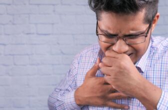 Người đàn ông đang ho và ôm vùng cổ họng, minh họa tình trạng ho gây khó chịu trong sinh hoạt hằng ngày.