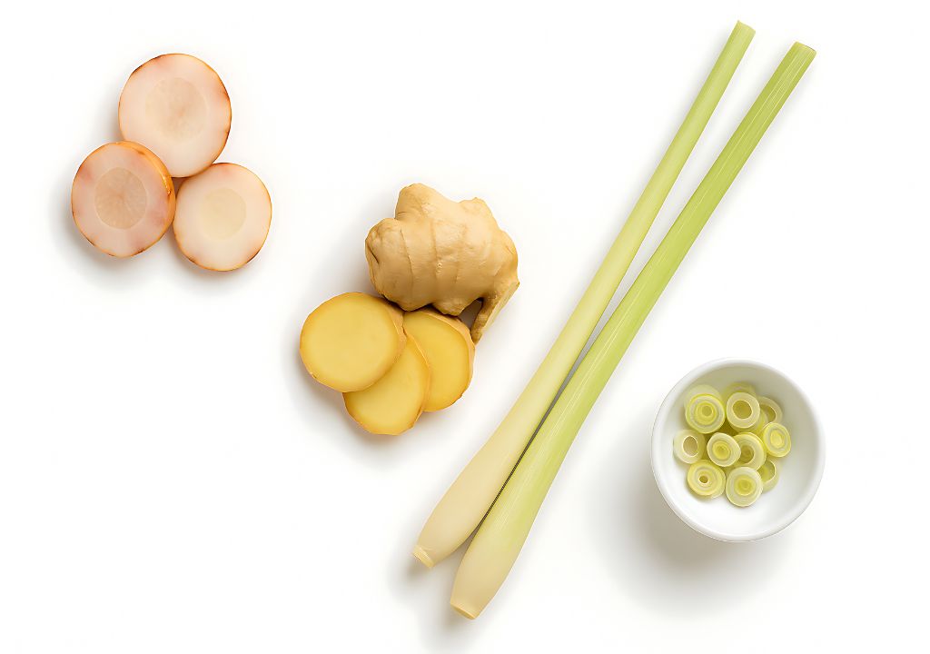 Gừng tươi, lát gừng cắt mỏng, sả cây và chén sả thái lát được bày trên nền trắng.