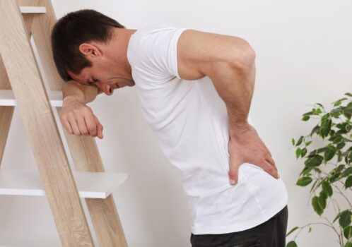Người đàn ông ôm lưng đau khi ho mạnh, biểu hiện ho đau lưng do căng cơ hoặc cột sống
