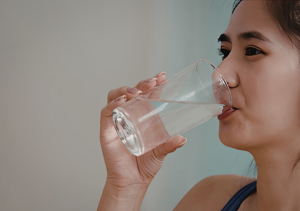 Người phụ nữ uống nước ấm giúp làm dịu cổ họng khi bị ho